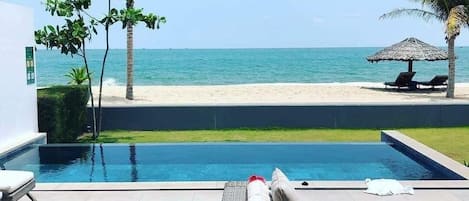 A poolside area with lounge chairs and a view of the beach.