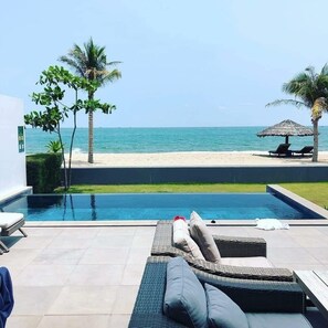 A poolside area with lounge chairs and a view of the beach. - Sanctuary Ho Tram Resort – Private Pool Villas (Ho Chi Minh City)