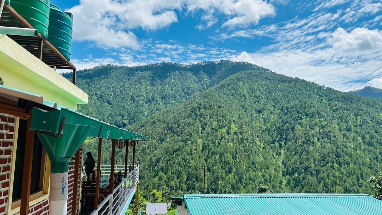A hotel with a balcony overlooking a forested mountain.