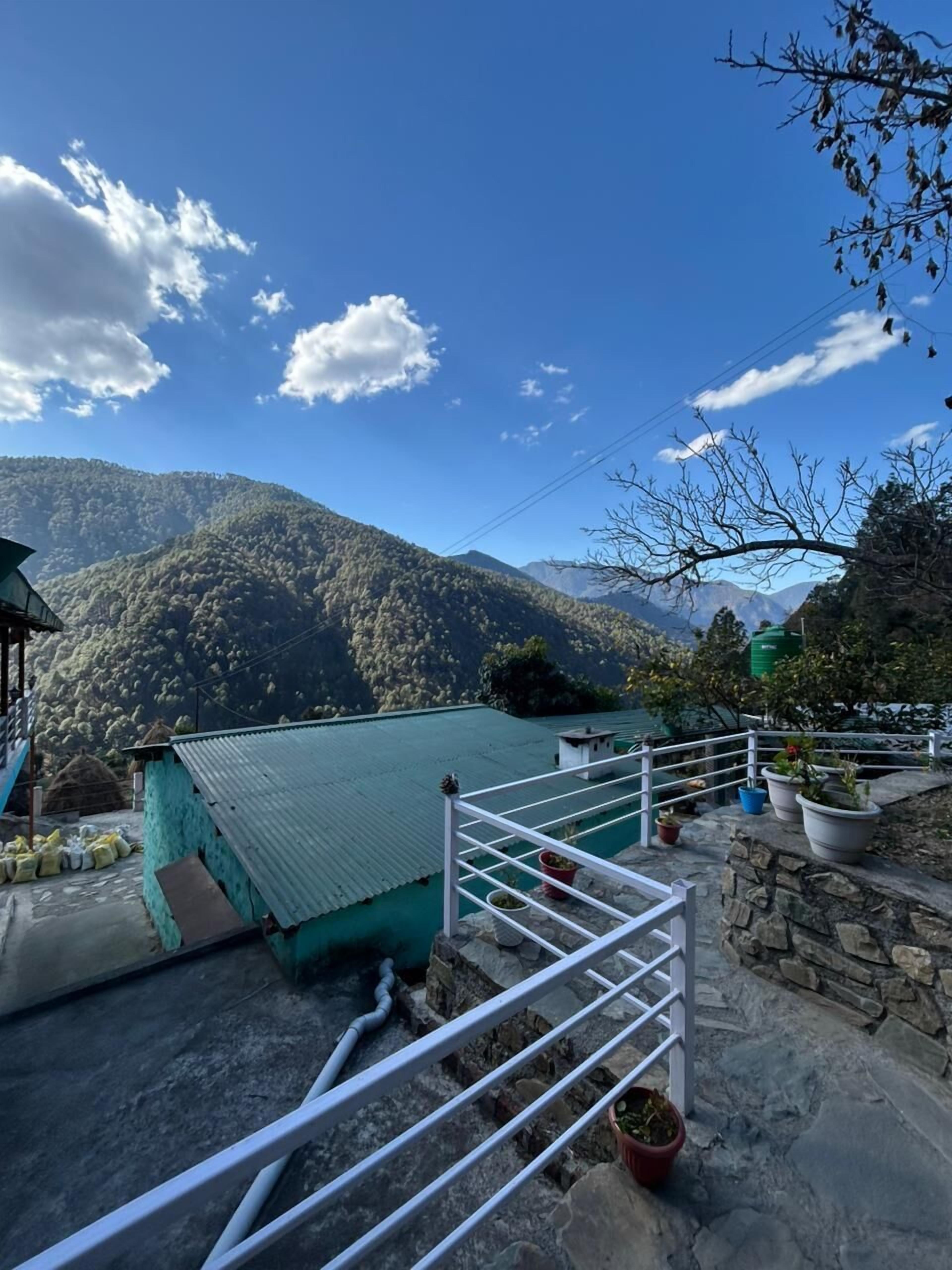 A mountainous landscape with a building featuring a green roof and white railings.