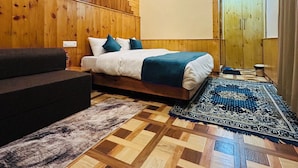 Ein Schlafzimmer mit einem Bett, einem Schlafsofa, einem Deckenventilator, einem Holzschrank und einem gemusterten Teppich.