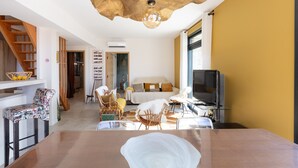 Een moderne woonkamer met een houten trap, een eethoek en een televisie.