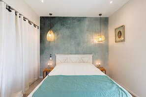 A bedroom with a bed, two bedside lamps, a nightstand, a wall-mounted picture, and a curtain. - Holiday Home 'In Chiusella Piscine De Rêve' with Sea View, Wi-Fi and Air Conditioning (Belgodère)