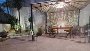 An outdoor patio area with a covered seating area, potted plants, and a decorative wall. - Etna Docet, Nicolosi center (Nicolosi)