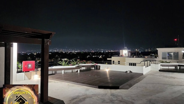 A rooftop terrace with a view of a cityscape at night. - Simpson's Little Gem 2 (Kingston)