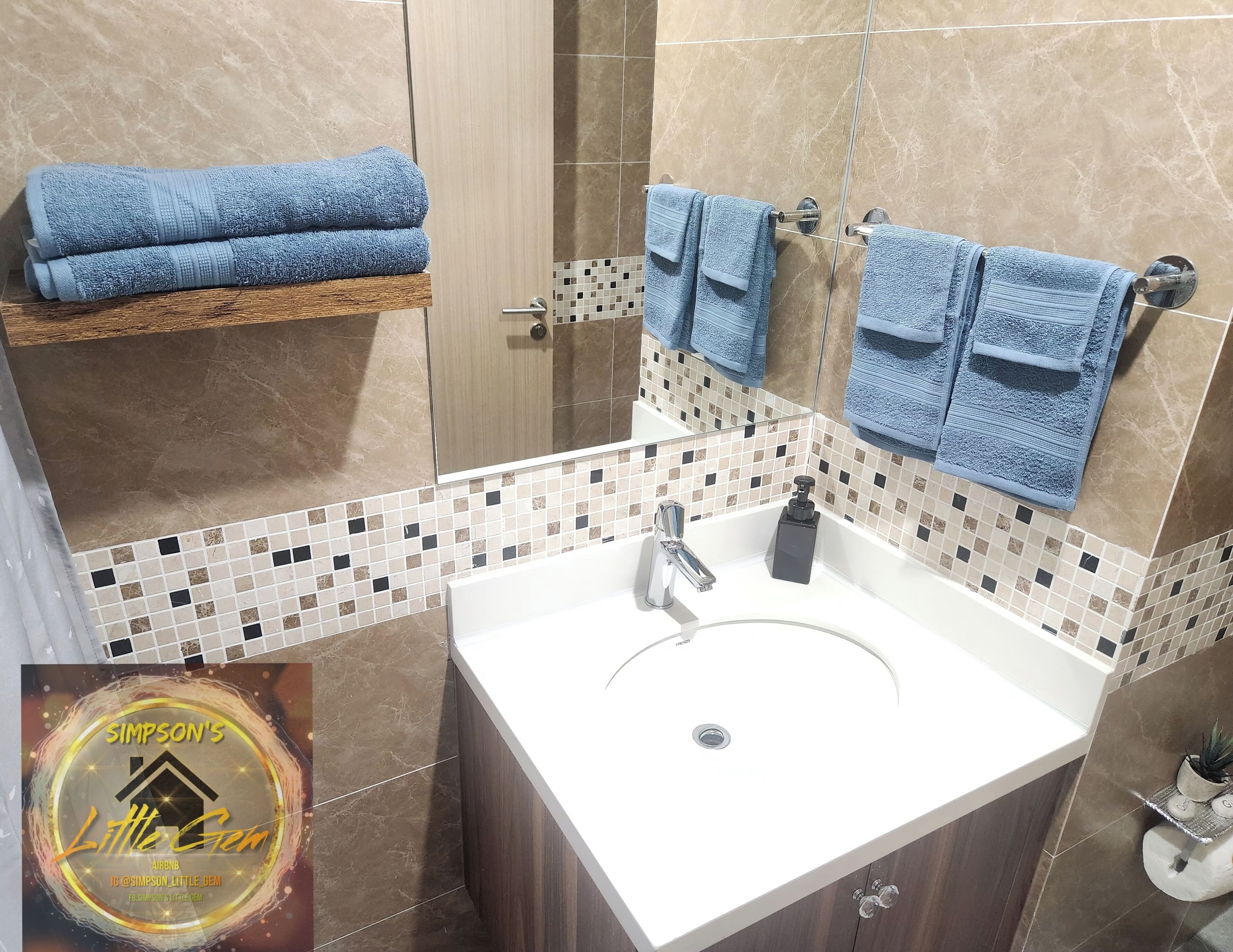 A bathroom with a white sink, a mirror, and blue towels on a rack and towel bar.