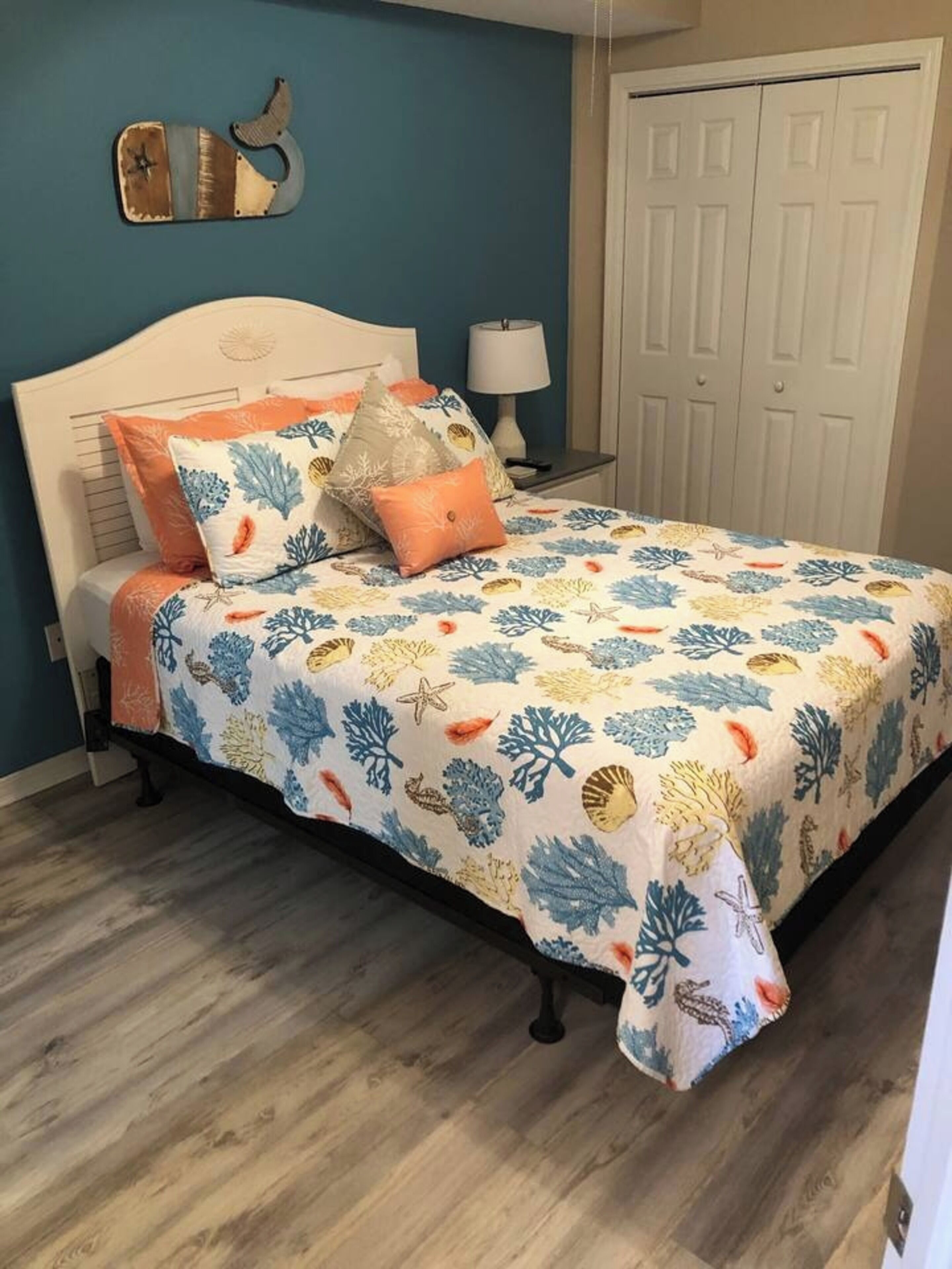 A bedroom with a bed, a nightstand, a lamp, and a door.