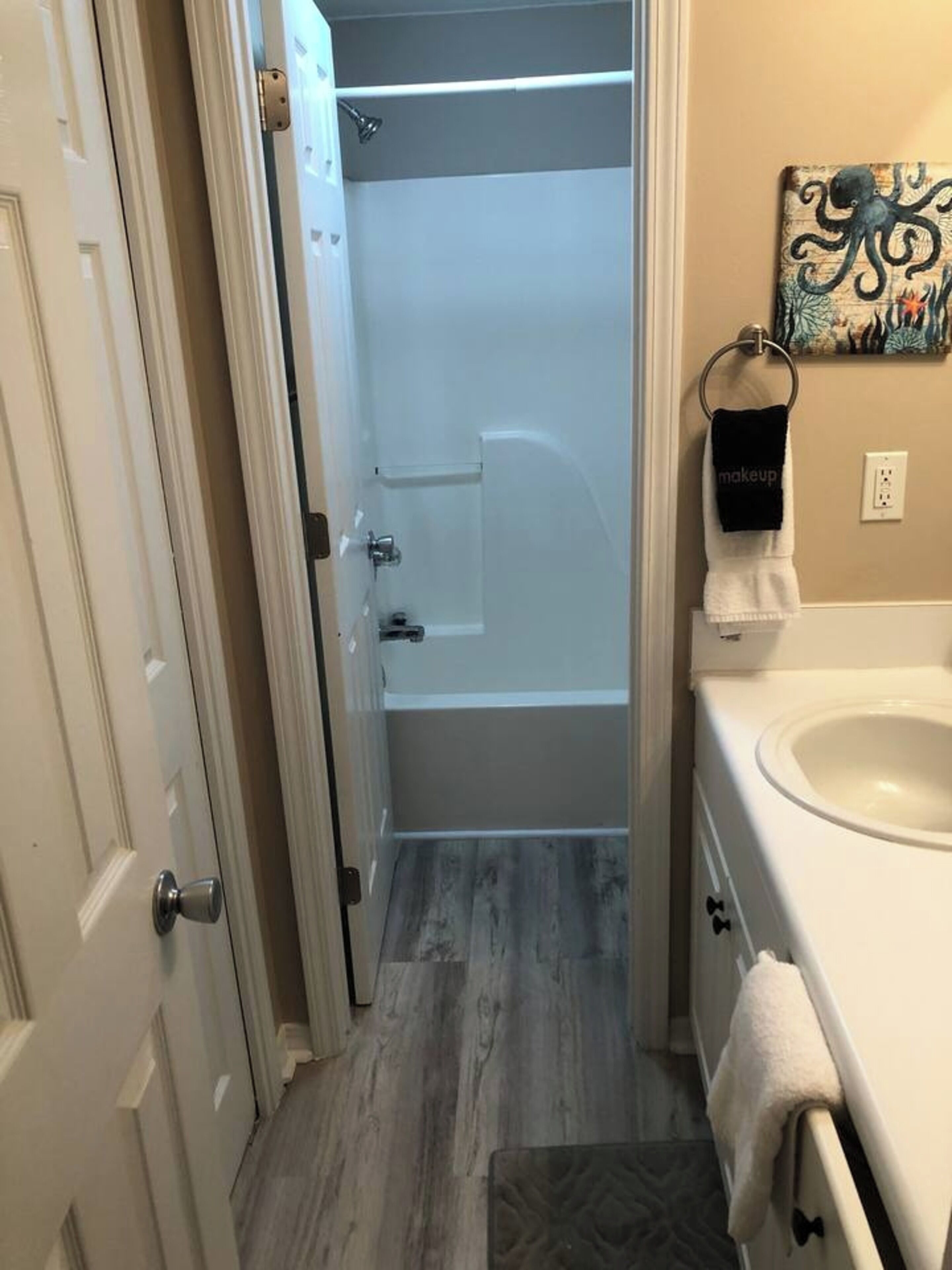A bathroom with a shower, a sink, and a towel rack.