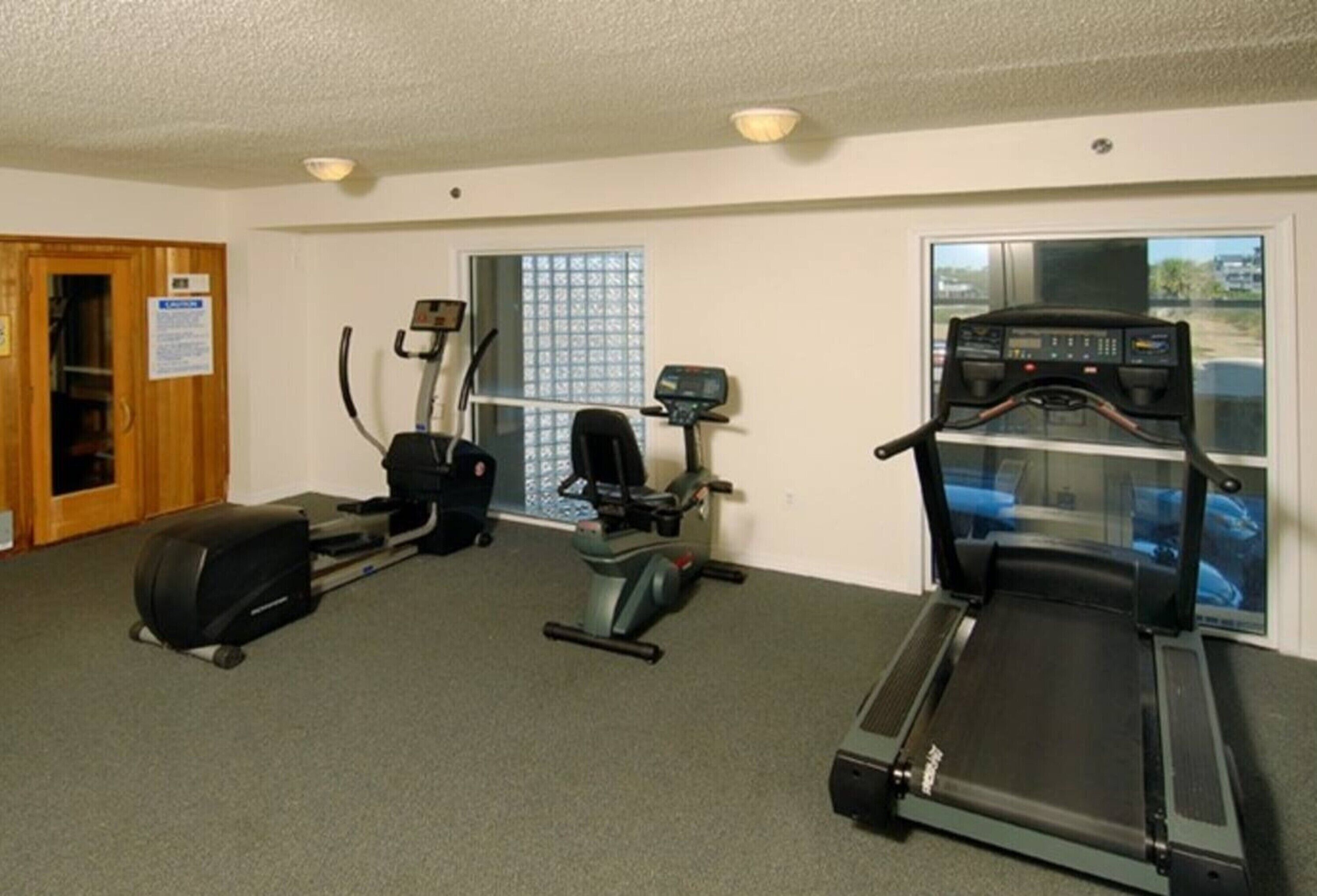 Un gimnasio con cintas de correr, elípticas y una bicicleta estática.