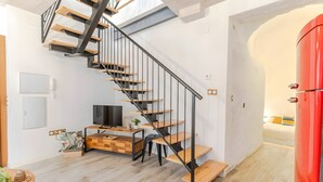 Ein modernes Interieur mit Treppe, Holzboden, Fernseher und einem roten Schrank.