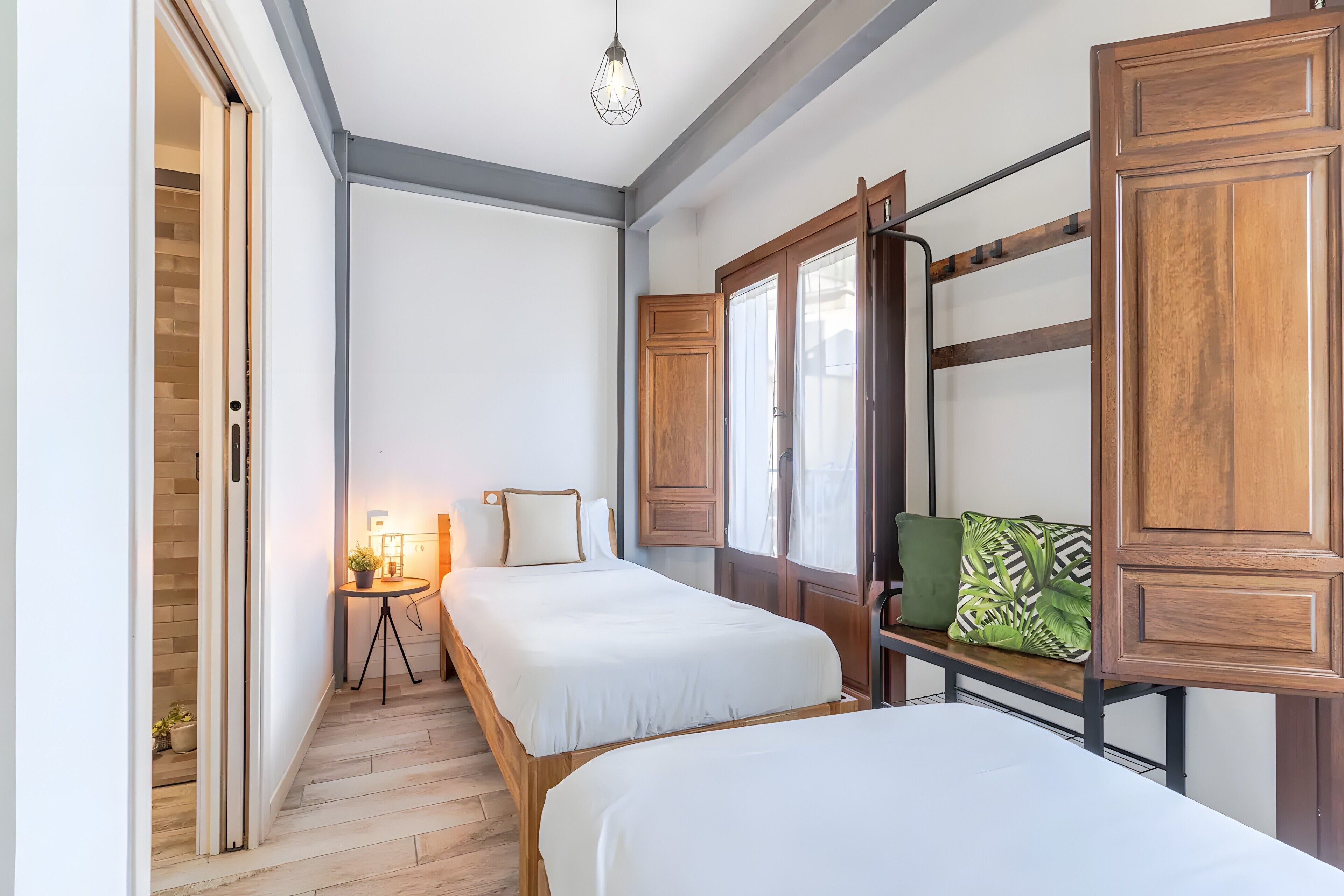 Une chambre avec deux lits, une petite table avec une lampe et des armoires en bois.