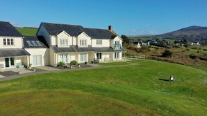 A large, two-story house with a well-maintained lawn and a small garden area. - Peg-y-Don : Stunning Holiday Cottage in Newport, Pembrokeshire (Newport)