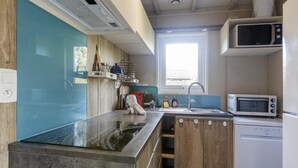 A compact kitchen with a built-in stove, microwave, and dishwasher. - Chalet 809 with all comforts on the edge of the forest (La Teste-de-Buch)