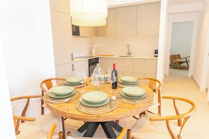 A dining area with a round wooden table set for six, surrounded by wooden chairs. - Lances Sun | Modern apartment in front of Los Lances Beach ideal for 6 travelers (Tarifa)