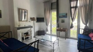 Ein Zimmer mit zwei Betten, einem Schreibtisch, einem Stuhl, einer Lampe und einem Fenster mit Vorhängen.
