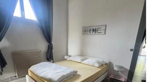 Ein Schlafzimmer mit einem Bett, einem Heizkörper, einem kleinen Tisch und einem an der Wand befestigten Schild.