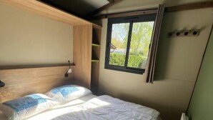 Un dormitorio con cama, ventana y cabecero.