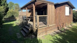 Una cabaña de madera con porche y un patio cercado.