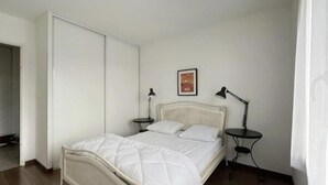 A bedroom with a bed, two bedside tables with lamps, a framed picture on the wall, and a wardrobe. - (P) T2 2 steps from the Bassin (Gujan-Mestras)