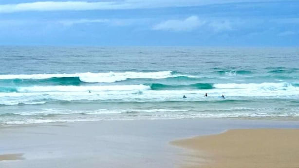 Una playa con olas y un cielo nublado.