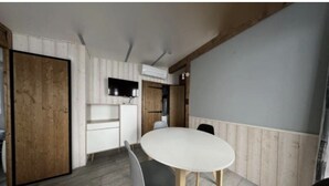 Una habitación con techo de madera, una mesa blanca y un televisor montado en la pared.