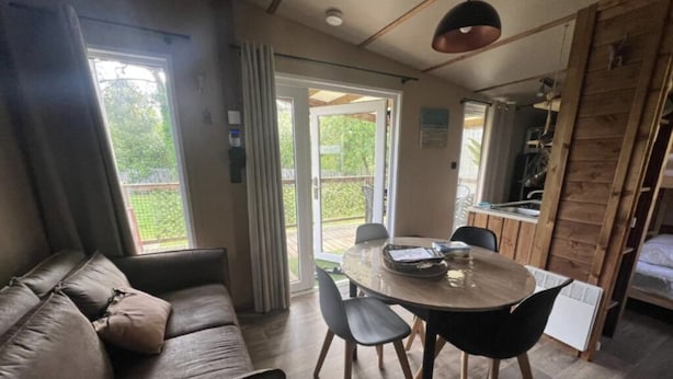 Ein gemütlicher Wohnbereich mit einer Couch, einem Esstisch und Stühlen. Eine Schiebetür führt auf einen Balkon.