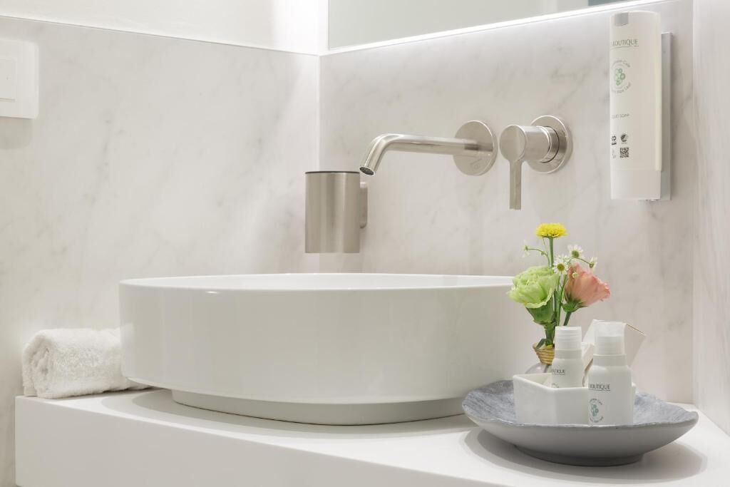 Une salle de bain moderne avec un lavabo rond blanc, une serviette et un petit vase avec des fleurs.