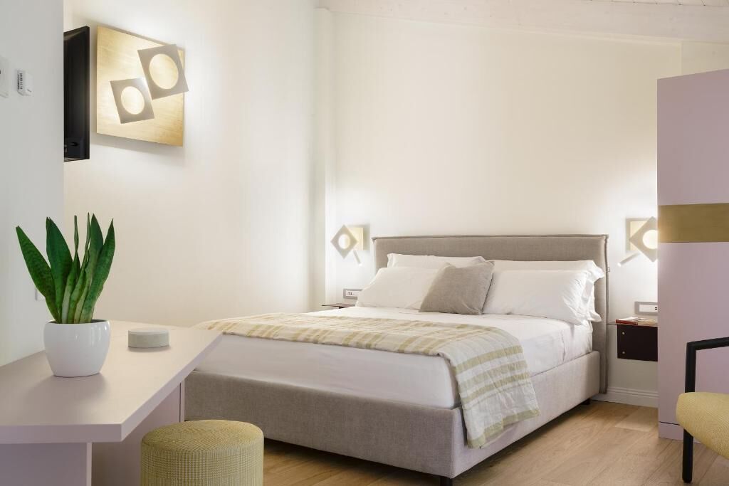 Un dormitorio moderno con una cama, mesitas de noche, una planta en maceta y un escritorio.