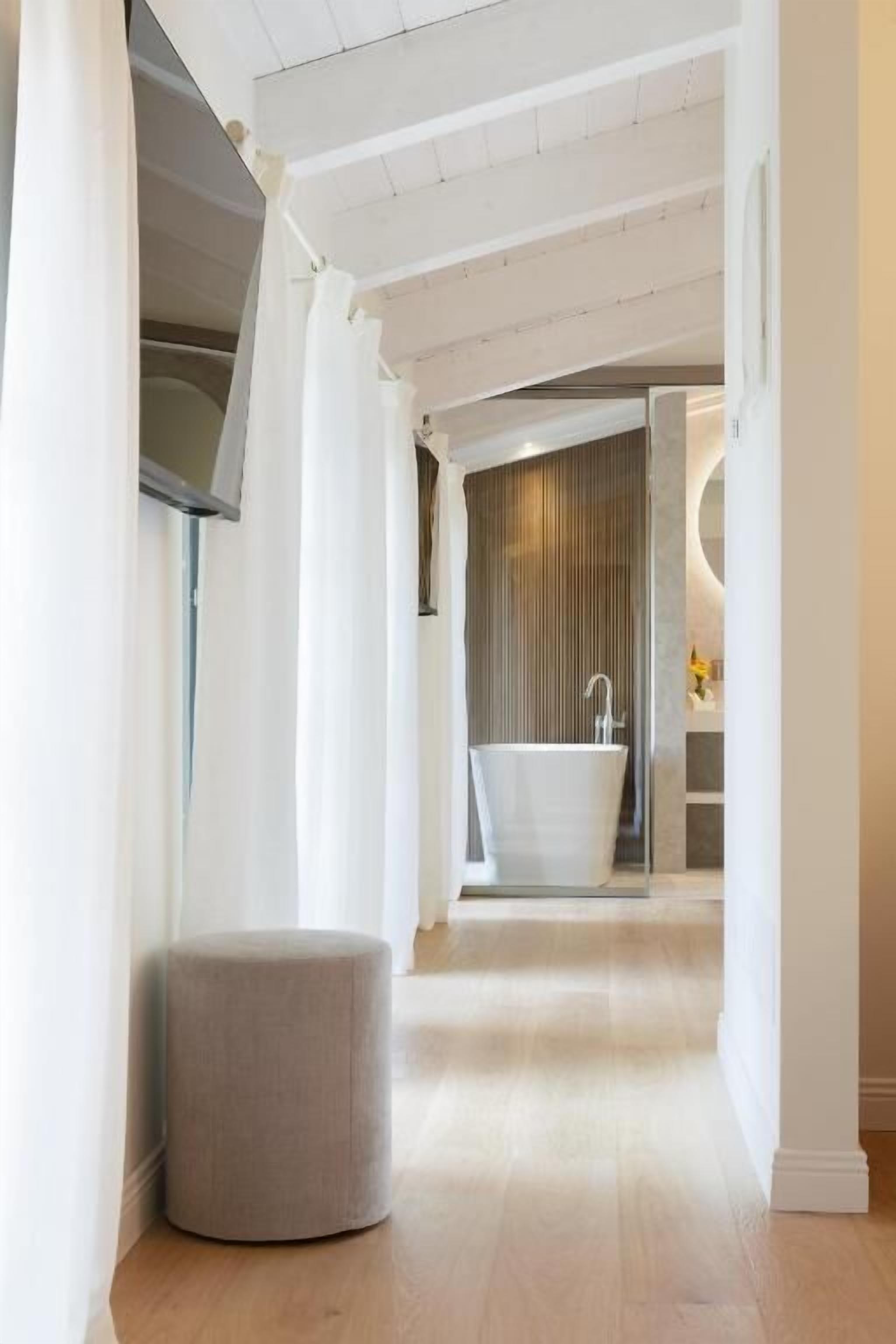Un baño moderno con una bañera independiente, un tocador y un espejo grande.