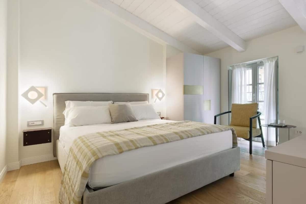 A bedroom with a bed, bedside tables, a chair, and a window with curtains.