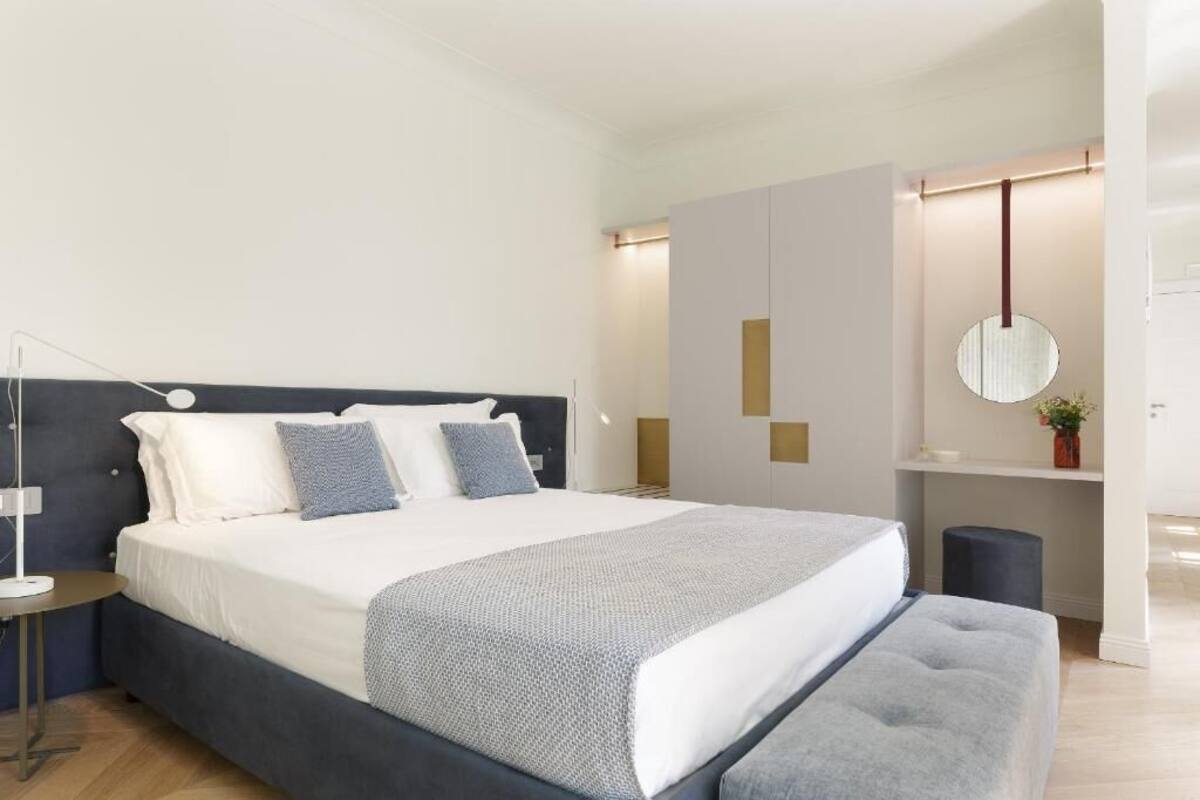 A modern bedroom with a large bed, bedside tables, and a round mirror.
