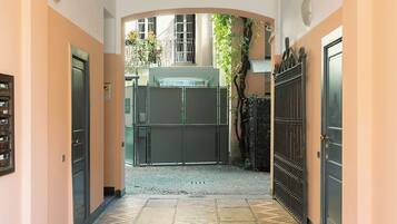 A corridor with a closed gate, a metal fence, and a building entrance.