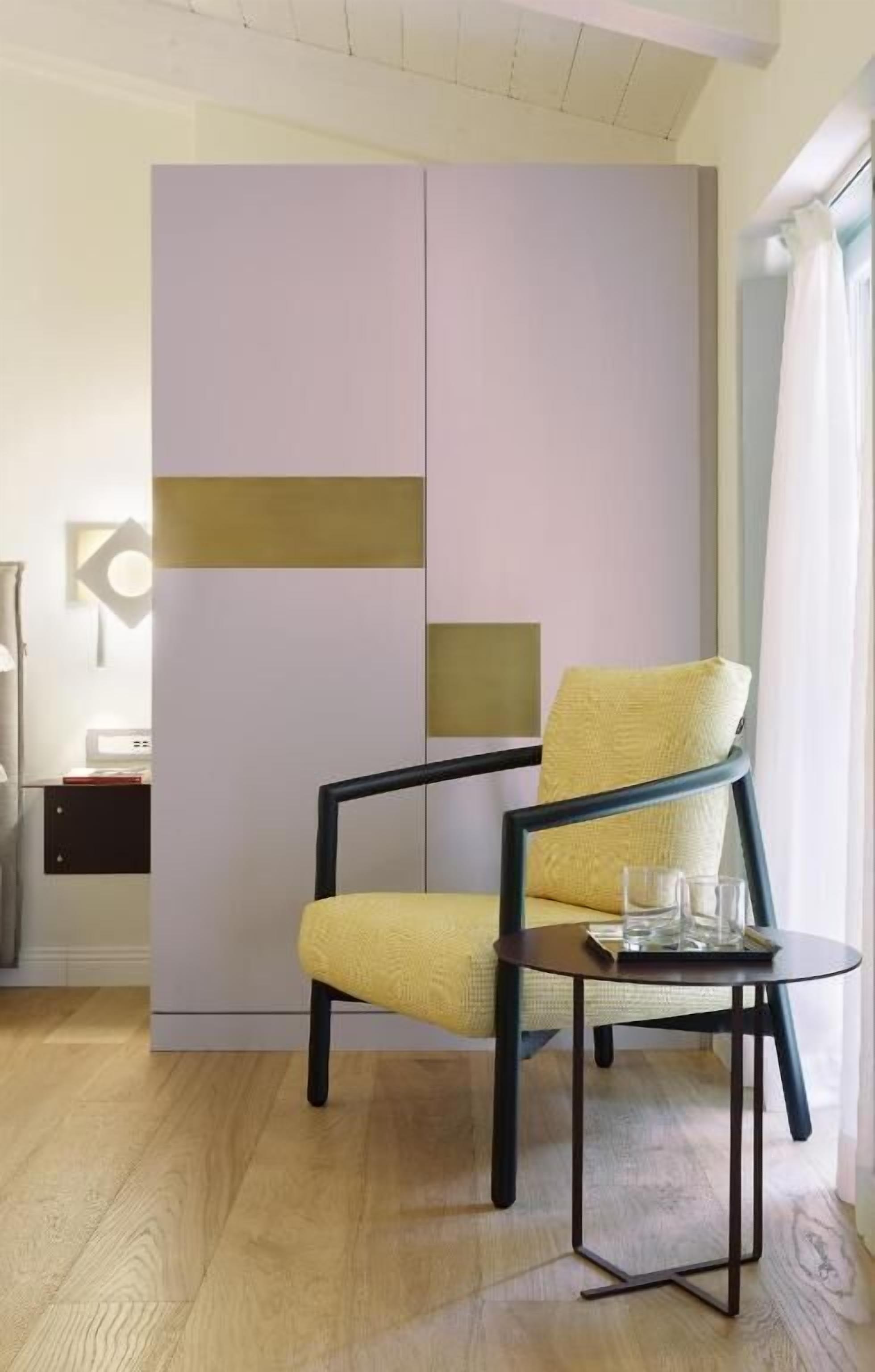 A modern room with a yellow chair, a small round table, and a wardrobe with a geometric design.