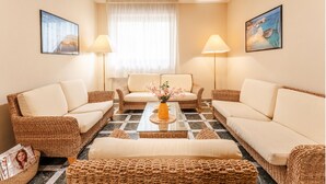 A cozy living room with wicker furniture, a central coffee table, and two lamps. - Charming and comfy apartment in Alghero (Alghero)