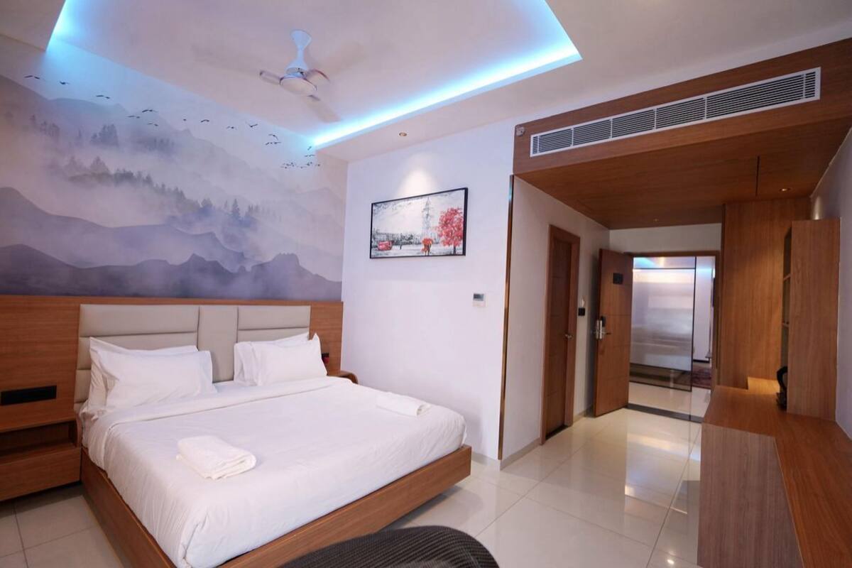 A modern hotel room with a large bed, a ceiling fan, a mural, and a door leading to a bathroom.
