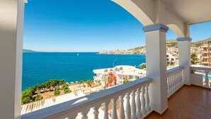 A balcony with a view of the sea and a coastal town. - Erdano Hotel (Sarande)