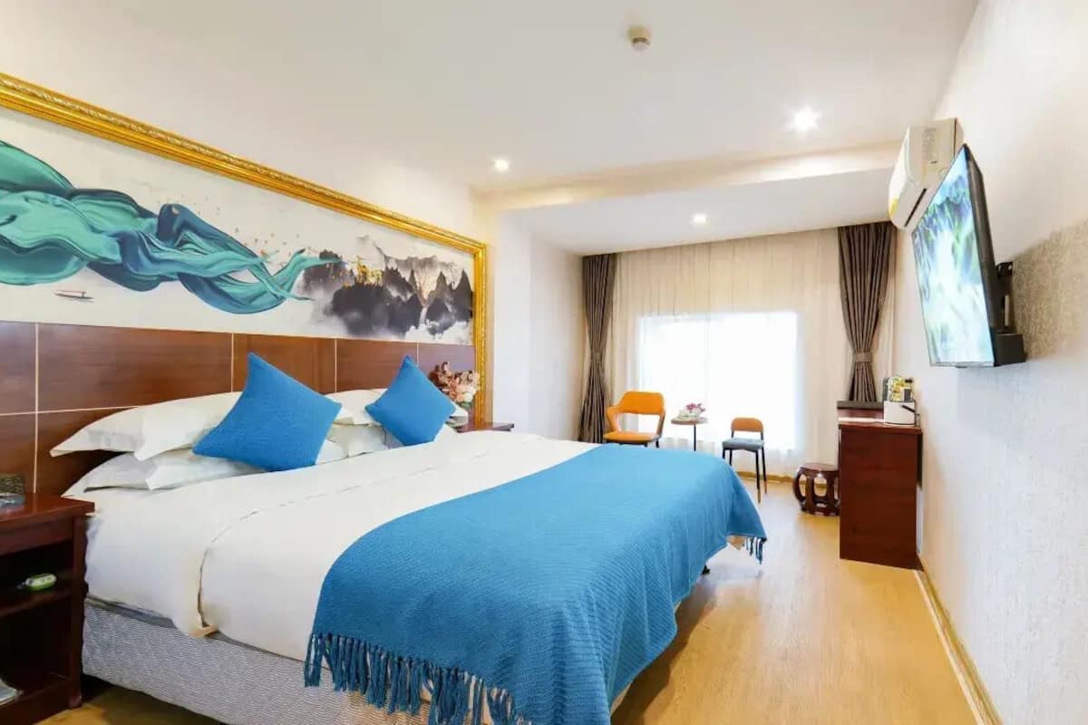 Een hotelkamer met een groot bed, een televisie, een bureau en een stoel.