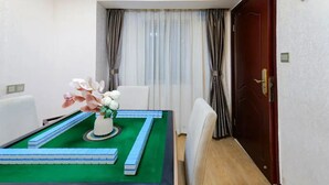 A room with a green carpet, white chairs, a table with a flower vase, and a door with a handle. - City-state Boutique Hotel (Shenzhen)