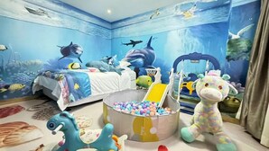 A room with a mural of an underwater scene, a bed, a ball pit, and various toys. - City-state Boutique Hotel (Shenzhen)