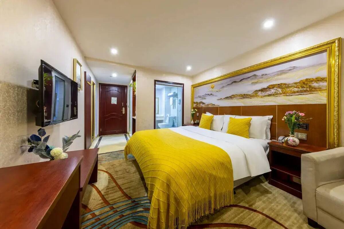 Een hotelkamer met een bed, een televisie, een bureau en een schilderij aan de muur.