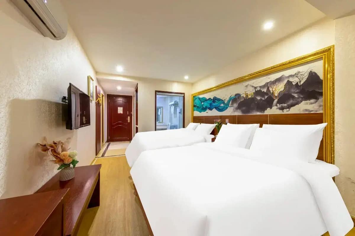 Een hotelkamer met een groot bed, een televisie, een bureau en een schilderij aan de muur.