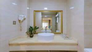 A bathroom with a white sink, a large mirror with a gold frame, a hairdryer, and a potted plant. - City-state Boutique Hotel (Shenzhen)