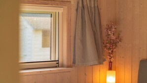A room with a window, a remote control, a lamp, and a vase with flowers. - Vacation home Seebrise with sauna, fireplace & rowing boat and beach directly on the Dümmer See. (Dümmer)