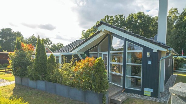 A modern building with a sloped roof, large windows, and a small porch. - Vacation home Seebrise with sauna, fireplace & rowing boat and beach directly on the Dümmer See. (Dümmer)