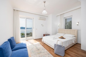 Ein Schlafzimmer mit einem Bett, einem blauen Sofa, einem Fenster mit Aussicht und einer Klimaanlage.