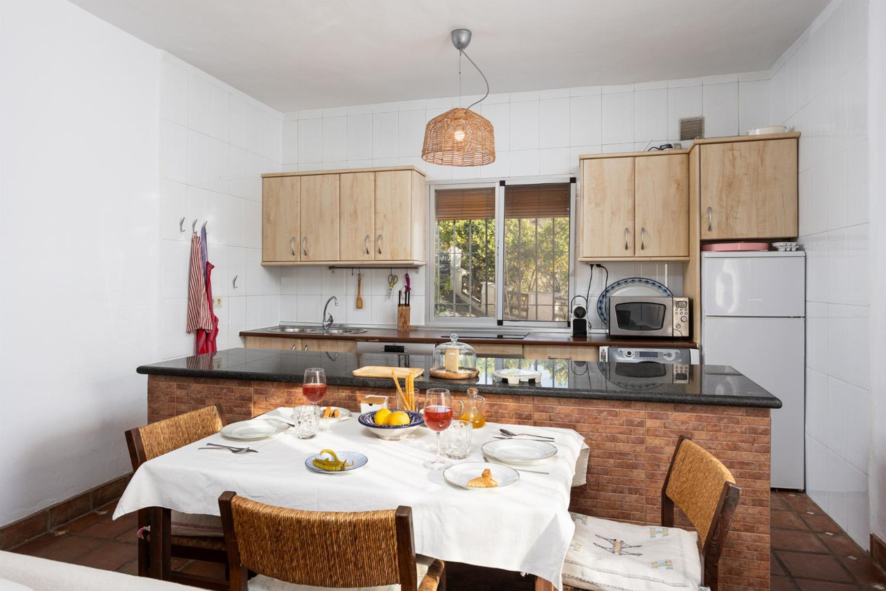 A kitchen with wooden cabinets, a black countertop, and a dining table set for four.