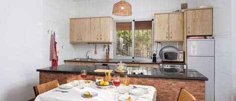 A kitchen with wooden cabinets, a black countertop, and a dining table set for four.