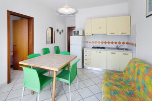 Cocina compacta con microondas, refrigerador y comedor con mesa y sillas.