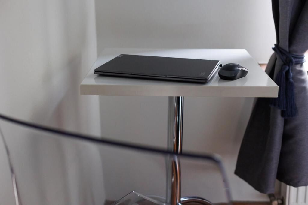 En bärbar dator står på ett vitt bord, och en mus ligger bredvid.