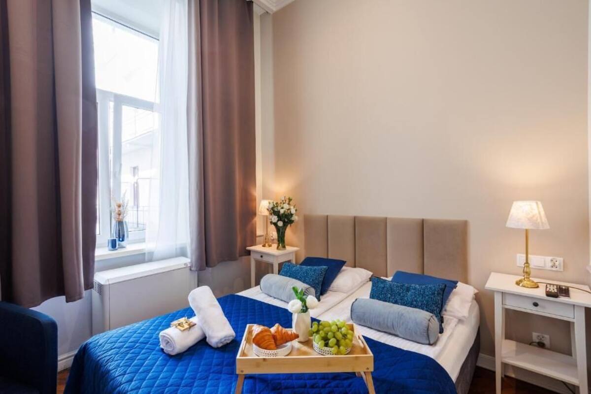 Ein Hotelzimmer mit einem Bett, einem Tablett mit Speisen und einem Nachttisch mit einer Lampe.